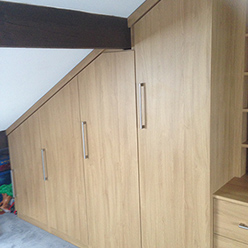 wood grain fitted wardrobes under sloped ceiling